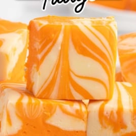 Orange creamsicle fudge stacked to show layered orange base and creamy white swirls