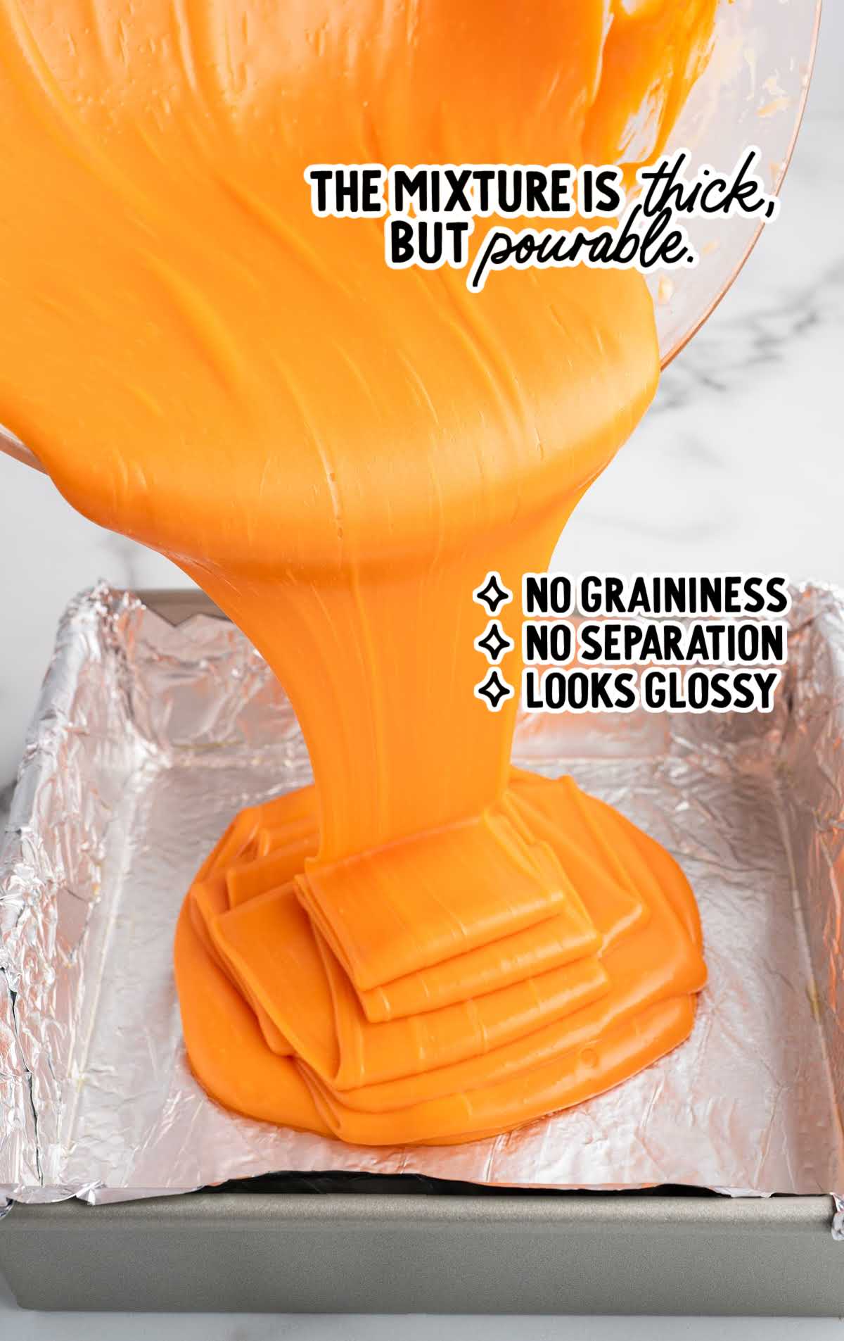 Thick glossy orange fudge mixture being poured into a foil lined baking pan
