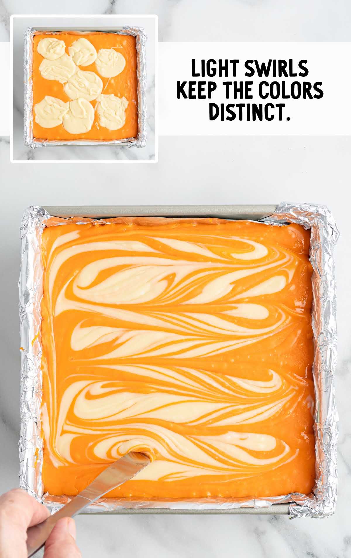 Swirling white chocolate into orange fudge in square baking pan to create marbled pattern