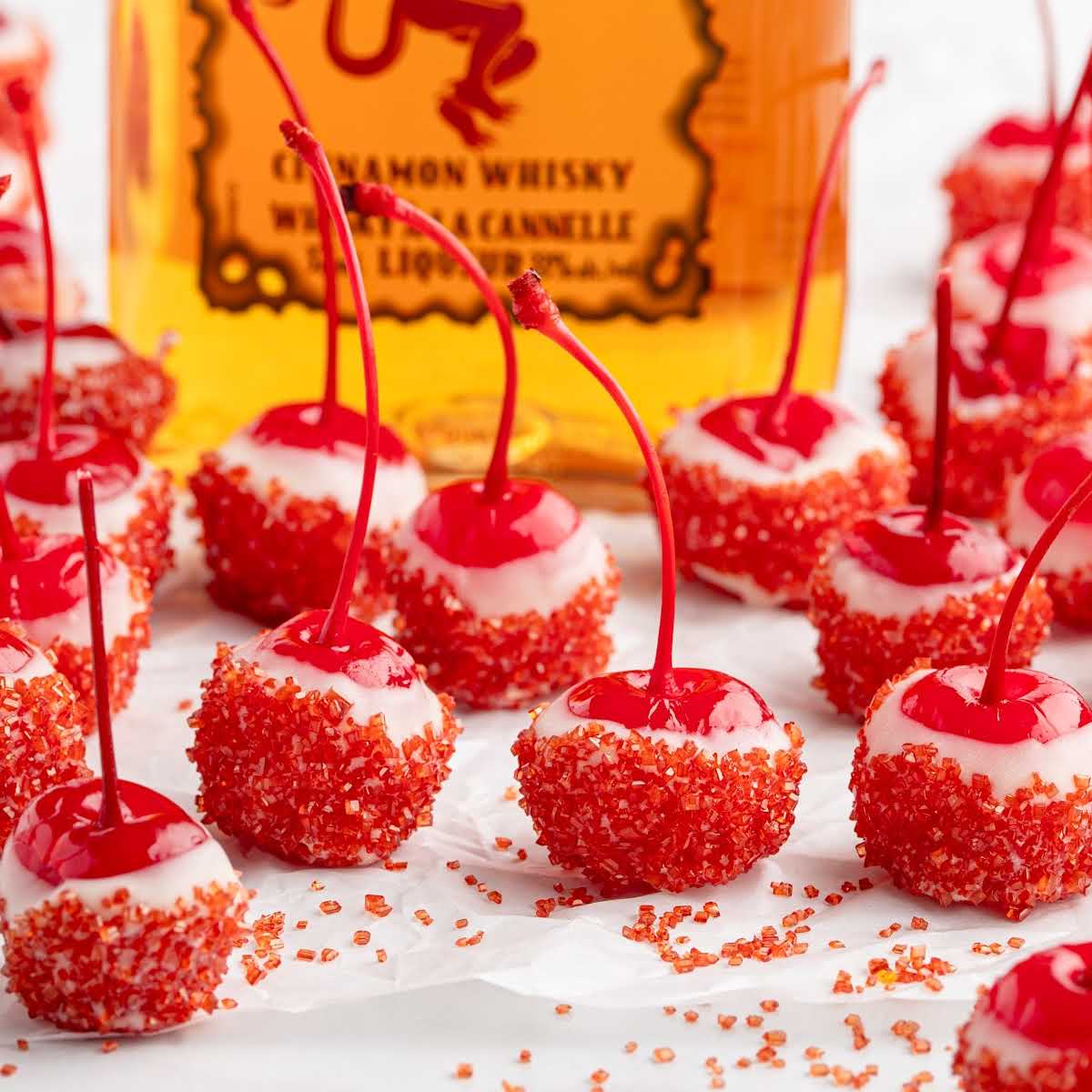 Fireball cherry bombs arranged on parchment paper in front of a Fireball whiskey bottle.