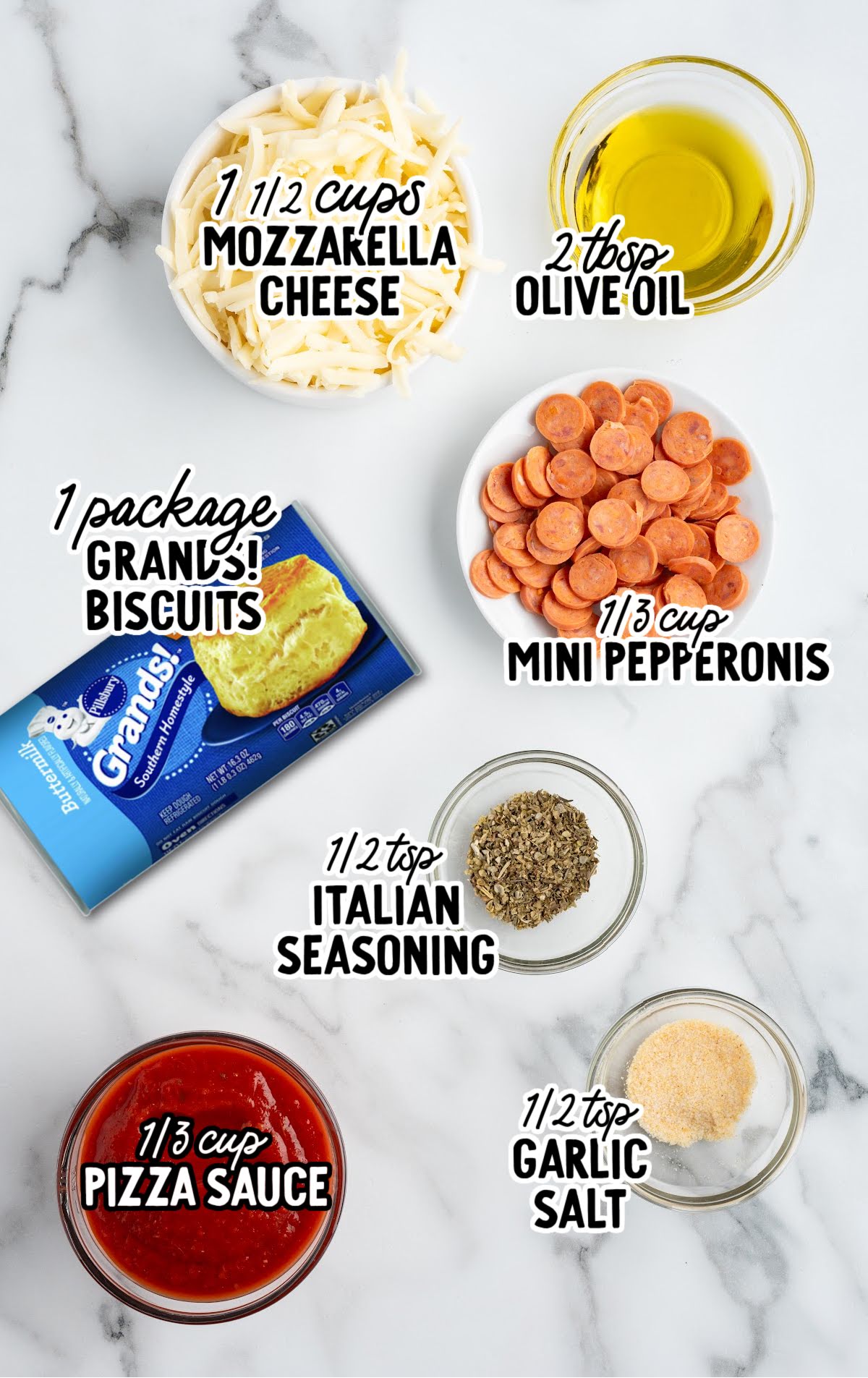 Overhead view of pizza pot pie ingredients including mozzarella cheese, mini pepperoni, Grands! biscuits, pizza sauce, olive oil, Italian seasoning, and garlic salt labeled in bowls.