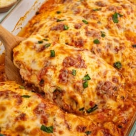 Serving of baked ricotta chicken lifted from the pan showing melted cheese and sauce