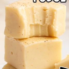 Three creamy yellow squares of eggnog fudge are stacked, with text reading The Best Eggnog Fudge Recipe and Vintage Recipe!! written in a bold, playful style.