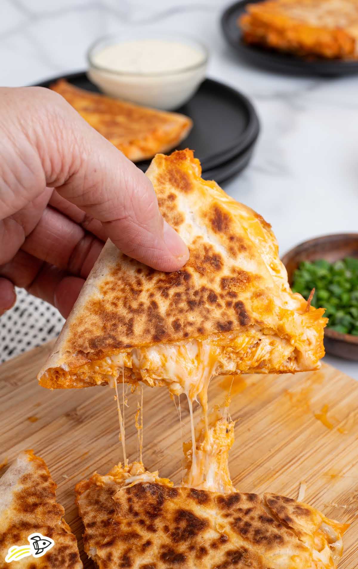 Buffalo chicken quesadilla being pulled apart with melted cheese stretch