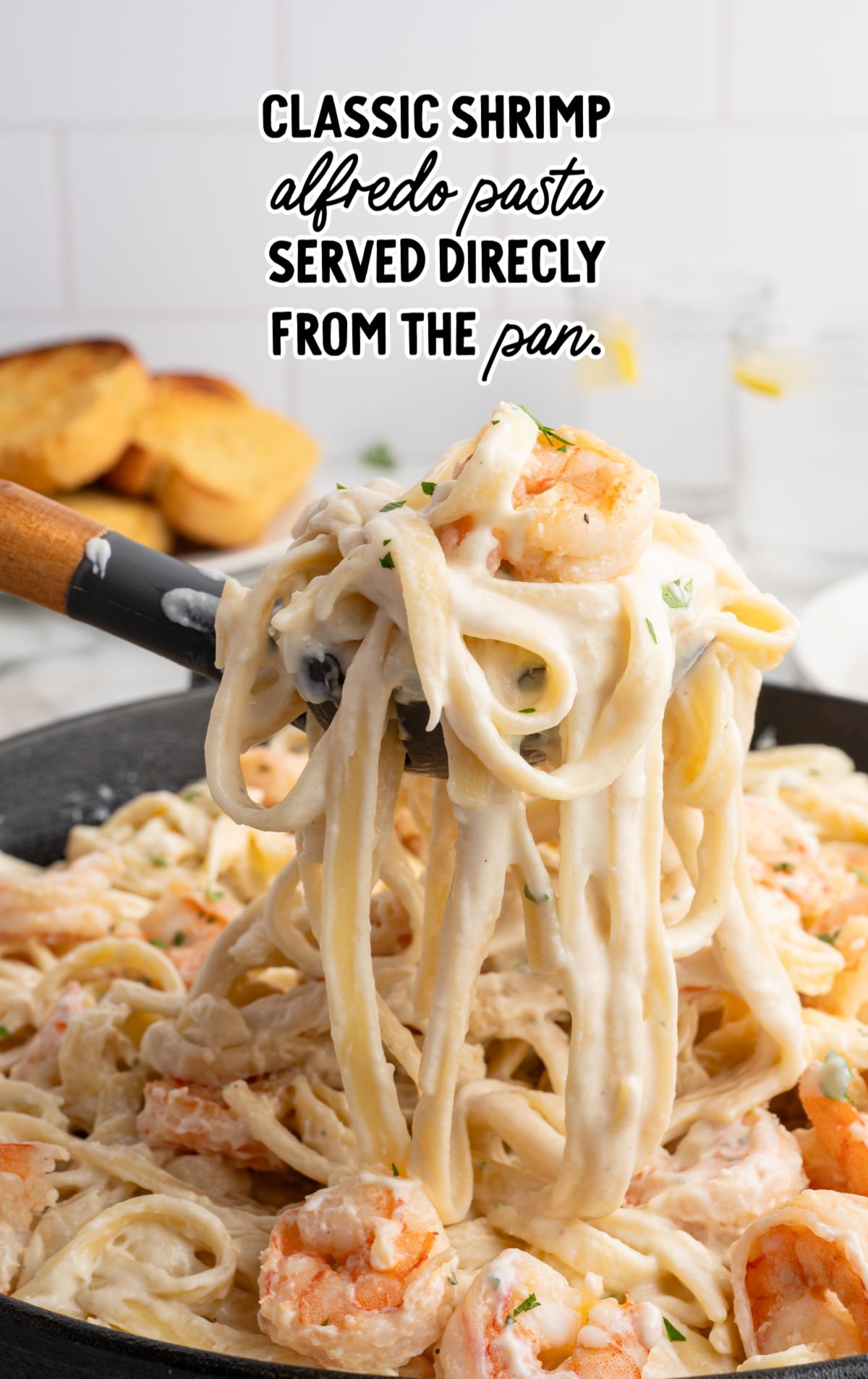 Skillet of shrimp alfredo pasta with fettuccine lifted from a cream-based Parmesan sauce.