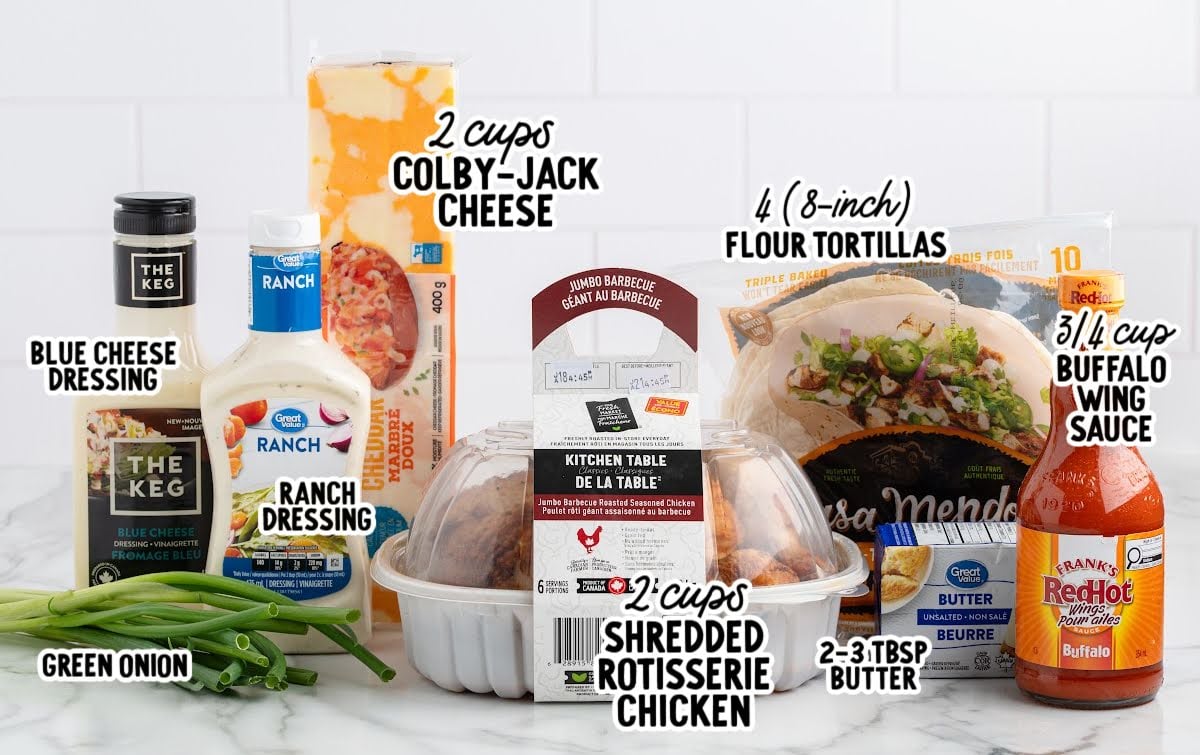 Ingredients for buffalo chicken quesadillas including shredded rotisserie chicken, colby-jack cheese, flour tortillas, buffalo wing sauce, butter, green onions, ranch dressing, and blue cheese dressing arranged on a counter.
