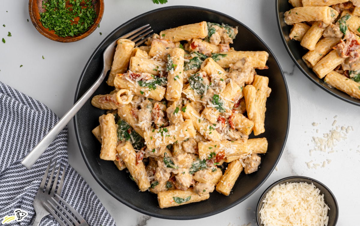 a bowl of creamy Italian sausage pasta with a fork