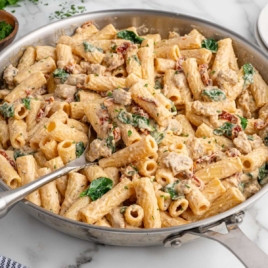 a skillet of creamy Italian sausage pasta with a fork