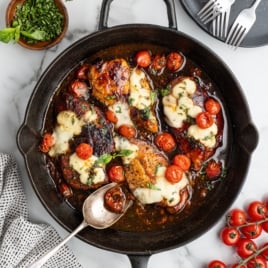 Close-up of balsamic chicken topped with melted cheese and blistered cherry tomatoes with a glossy balsamic glaze.