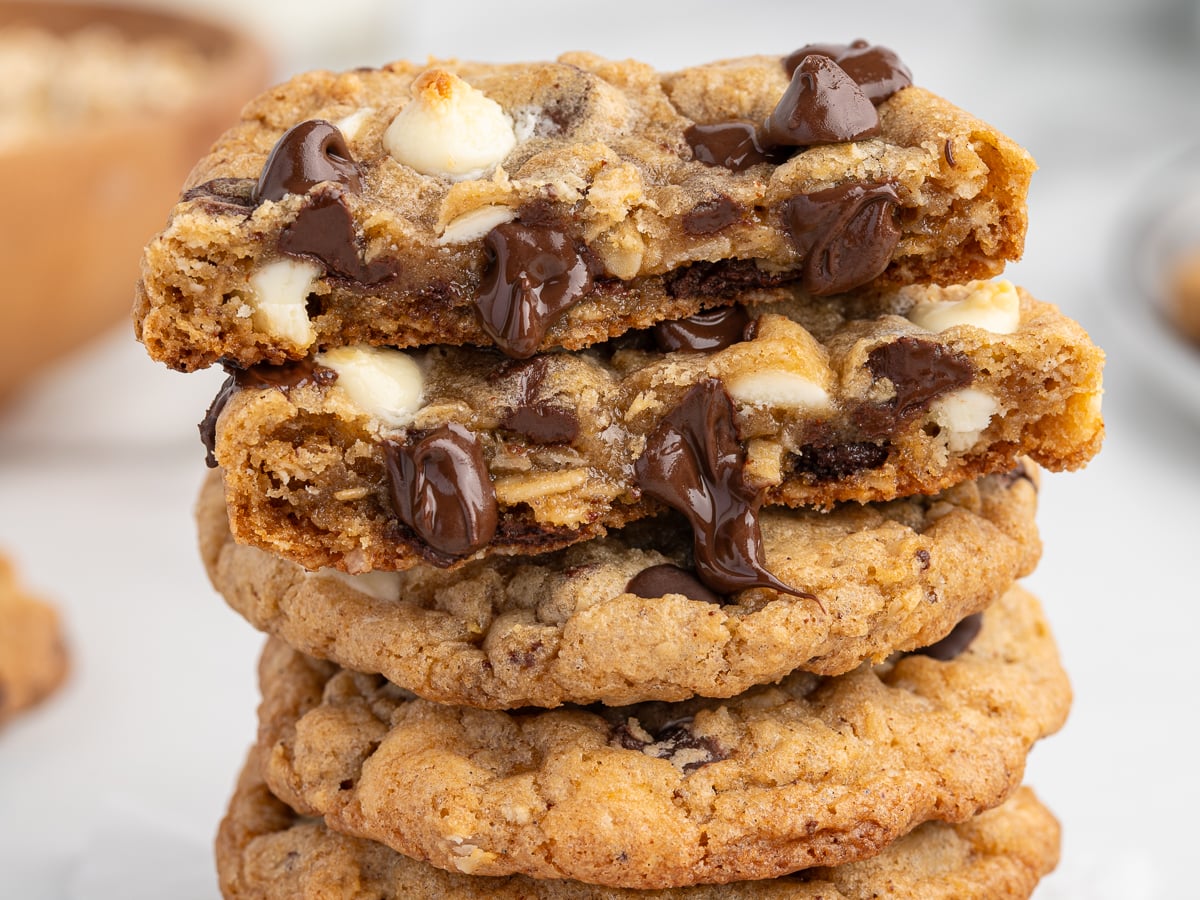 A stack of Marry Me Cookies&mdash;oatmeal chocolate chip&mdash;with the top cookie broken in half to reveal gooey melted dark and white chocolate chips inside.