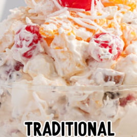 A glass dish filled with creamy Ambrosia Salad, topped with shredded coconut and a maraschino cherry. The image features text reading vintage recipe and Traditional Ambrosia Salad.