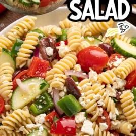 Close-up of a bowl of Greek Pasta Salad featuring rotini, cucumber, tomato, olives, red onion, feta, and bell pepper. In the background, dressing is being poured onto a separate bowl of salad. Text reads Greek Pasta Salad—a fresh and vibrant Greek Salad Recipe perfect for any occasion.